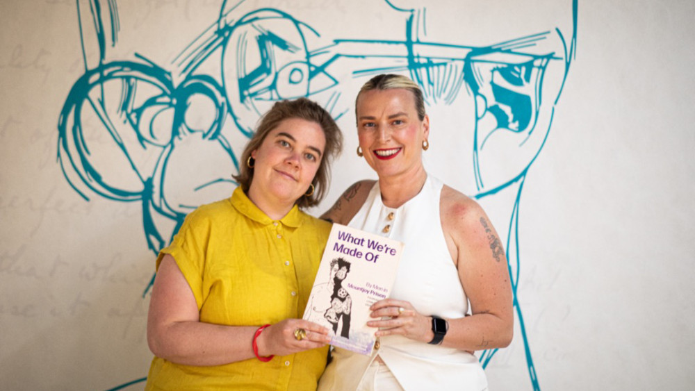Photograph of two women holding a book titled 'What We're Made Of'.